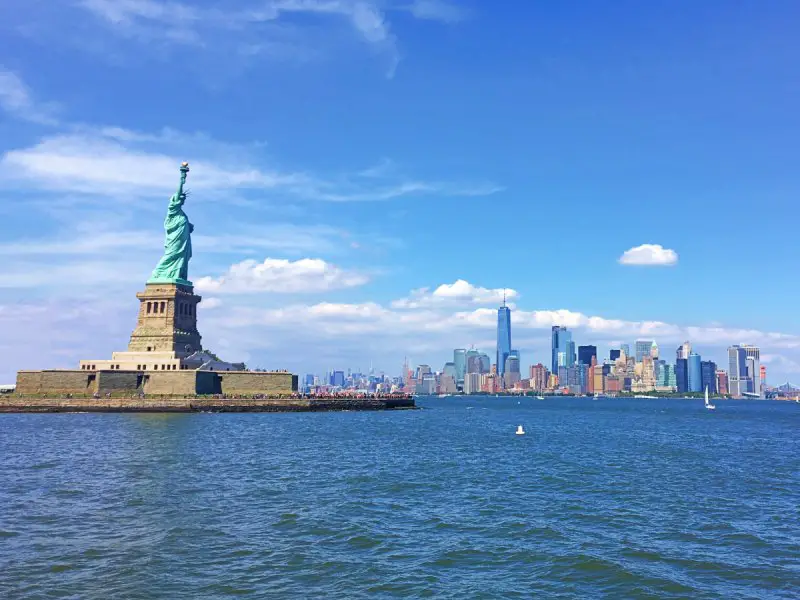 statue of liberty and new york skyline seen from a boat