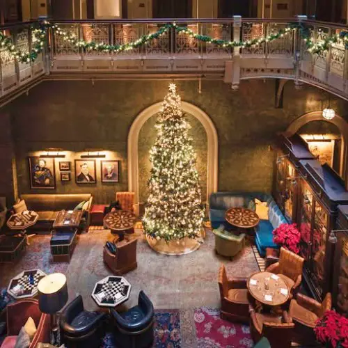 hotel lobby area with several chairs scattered around and a large christmas tree seen from balcony above