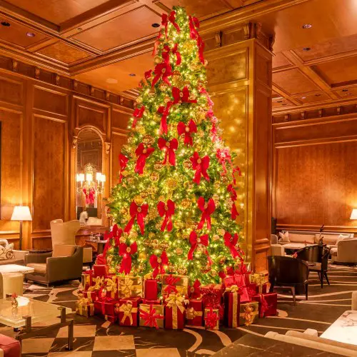 christmas tree in hotel lobby with presents at base and chairs around it